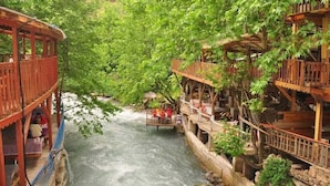 Eine Holzbrücke über einem Fluss mit Sitzgelegenheiten und einem Gebäude mit Balkonen.