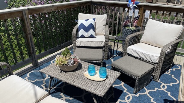 A deck with wicker furniture, including chairs and a table with cushions and a potted plant. - Historic 1895 Queen Anne Victorian that is 131 years young (Lead)