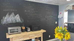 A kitchen with a chalkboard wall displaying various messages and a wooden counter with kitchen appliances. - Historic 1895 Queen Anne Victorian that is 131 years young (Lead)