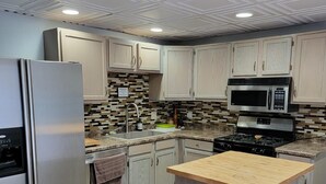 A modern kitchen with light wood cabinets, stainless steel appliances, and a central island. - Historic 1895 Queen Anne Victorian that is 131 years young (Lead)