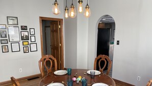 A dining room with a round wooden table, four chairs, and a chandelier. - Historic 1895 Queen Anne Victorian that is 131 years young (Lead)