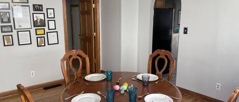 A dining room with a round wooden table, four chairs, and a chandelier.