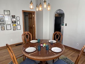 A dining room with a round wooden table, four chairs, and a chandelier.