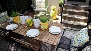 Een houten eettafel gedekt met witte borden, glazen en een ananas als middelpunt.