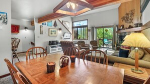 Un vaste espace de vie comprenant une table à manger en bois, des sièges confortables et une grande fenêtre donnant sur un paysage verdoyant.