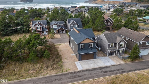 Et boligområde med huse, en vej og udsigt til havet.