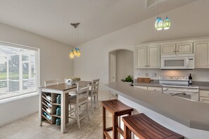 A kitchen with a central island, white cabinets, a microwave, and a stove.
