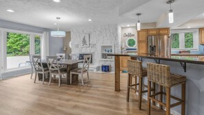 Una cocina moderna con comedor, suelo de madera y una pared decorativa de piedra.