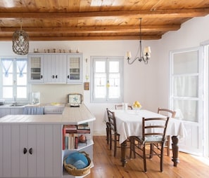 A kitchen with a central island, wooden cabinets, and a dining area with a table and chairs.