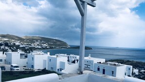 A white building with a balcony overlooking a coastal town and the sea. - Tinos Agios Sostis Villa Filippos  five (5) min  walk to the beach - Pet Allowed (Agios Sostis Tinos)