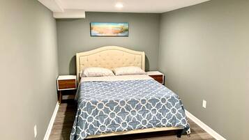 A bedroom with a bed, nightstands, a painting on the wall, and a wooden floor.