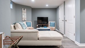 Un salon avec un canapé beige, un téléviseur et un panneau fixé au mur.