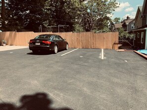 A parking lot with a black car parked in the foreground. - Semi Private cozy studio near downtown. (Montclair)