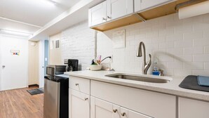 Une cuisine moderne avec des meubles blancs, un évier en acier inoxydable et une machine à café.