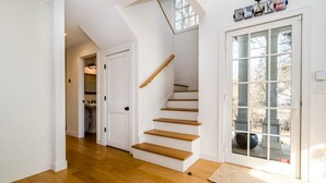 Un escalier avec des marches en bois et une rampe, menant à une porte dotée d’un panneau de verre.