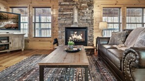 Un salon chaleureux avec une cheminée en pierre, des murs en bois, un canapé en cuir et une table basse.