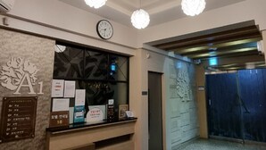 Et hotellets receptionområde med et moderne loftdesign, et ur og en receptionsdisk med informationsskilte.