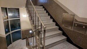 En trappe med metalgelændere og gelænder, der fører til en platform med glasvæg og et metalskabe.