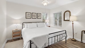 A bedroom with a bed, bedside tables, a floor lamp, and framed artwork on the wall.