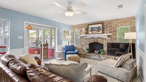 A living room with a brick fireplace, leather sofas, and a television.