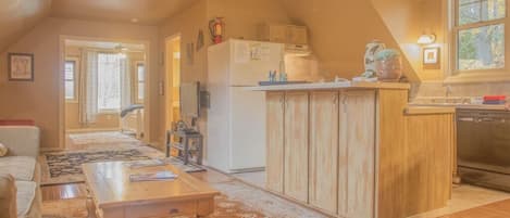 Une cuisine chaleureuse avec des meubles en bois, un coin repas avec une table et des chaises, et une vue sur l’extérieur par une fenêtre.