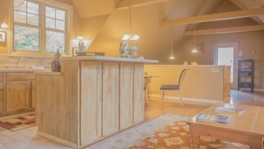 Een keuken met houten kastjes, een groot eiland en hangende lampen.