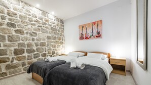 Een slaapkamer met twee bedden, een stenen muur en een schilderij van gitaren.