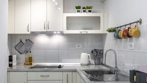 Een moderne keuken met witte kasten, een roestvrijstalen spoelbak en diverse keukengerei en apparaten.