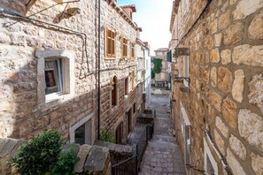 A narrow stone street flanked by historic buildings with arched doorways and wooden shutters. - Beautiful property within the city walls (Dubrovnik)
