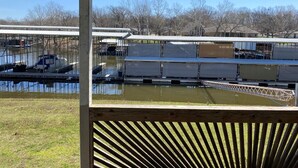 A view of a boat docked at a marina with a wooden deck in the foreground. - Cozy 2 Bed 2 Bath Lake Front Cottage (Afton)