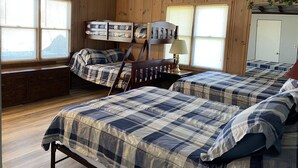 A cabin-style room with two bunk beds, wooden walls, and a large window. - Cozy 2 Bed 2 Bath Lake Front Cottage (Afton)