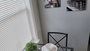 A dining table with two chairs, white plates, cutlery, and a small potted plant. - Newly remodeled 1 Bedroom apartment (Ypsilanti)