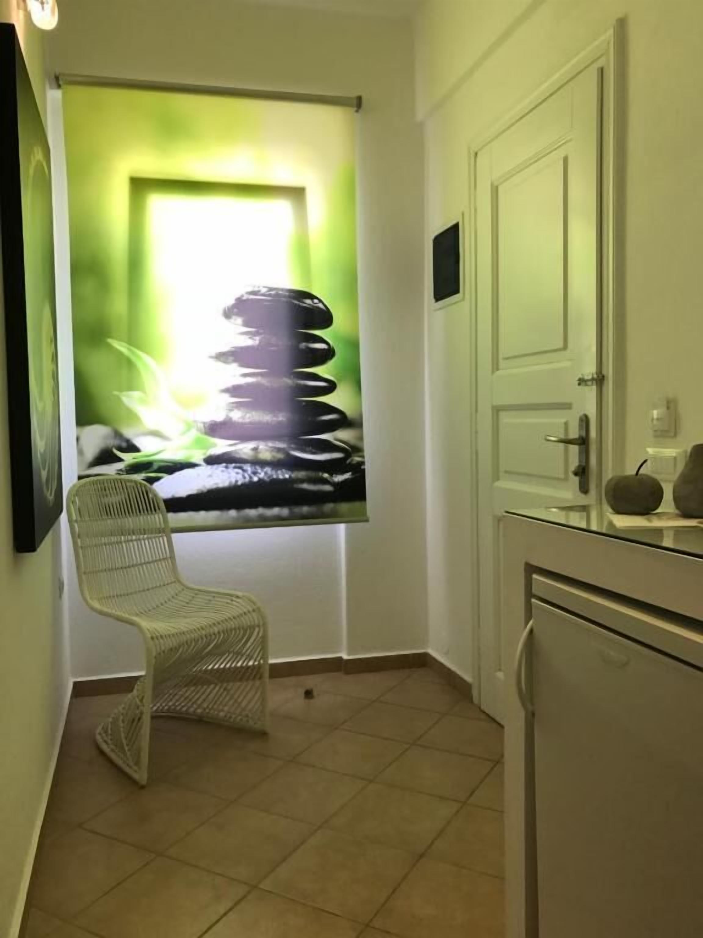Quarto pequeno e limpo com uma cadeira, uma porta e piso de azulejos.
