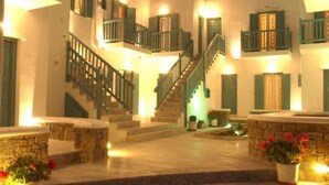 Un edificio con varios balcones, una escalera central y plantas en macetas.