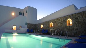 Piscina con sillas de descanso y paredes de piedra.