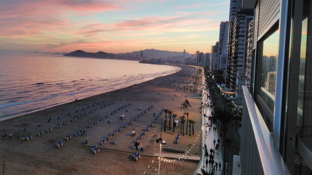 A beach with rows of sun loungers and a city skyline in the background. - Waterfront apartment Levante beach , in waterfront promenade. Great views (Benidorm)