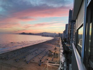 A beach with rows of sun loungers and a city skyline in the background. - Waterfront apartment Levante beach , in waterfront promenade. Great views (Benidorm)