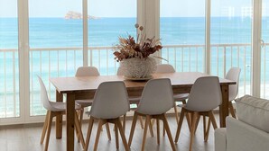 A dining area with a view of the sea, featuring a wooden table, white chairs, and a decorative vase. - Waterfront apartment Levante beach , in waterfront promenade. Great views (Benidorm)