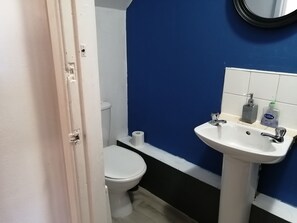 Ein Badezimmer mit einem weißen Waschbecken, einer Toilette und einer blauen Wand.