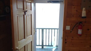Een houten hutje met een deur die uitkomt op een balkon.