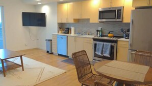 A modern kitchen with wooden cabinets, a microwave, a refrigerator, and a dining area with a table and chairs. - Space Needle and Mountain View. Top-Floor Condo (Seattle)