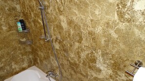 A bathroom with a bathtub, a shower, and a towel rack.