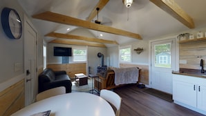 Interior acolhedor de uma cabana com sala de estar, mesa de jantar, cozinha e lareira.