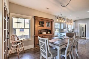 Una cocina amplia con una mesa de comedor de madera, sillas blancas y un ventanal grande.