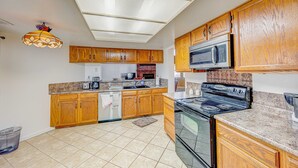 A kitchen with wooden cabinets, a stove, a microwave, and a ceiling light fixture. - Sunny, functional, Central NW --Super Clean (Albuquerque)