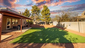 A backyard with artificial grass, a patio area with outdoor furniture, and a view of the sky. - Sunny, functional, Central NW --Super Clean (Albuquerque)