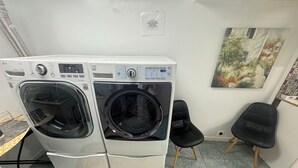 Ein Waschraum mit zwei Waschmaschinen mit Frontlader, einem schwarzen Stuhl und einem Teppich mit der Aufschrift 'laundry room'.