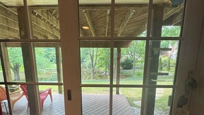 Eine Holzterrasse mit einer Glastür, die zu einem Außenbereich mit Stühlen und einem Rasen führt.