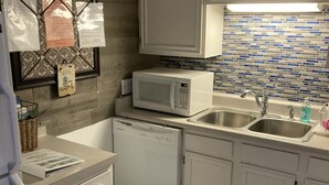 A compact kitchen with white cabinets, a microwave, a dishwasher, and a sink.