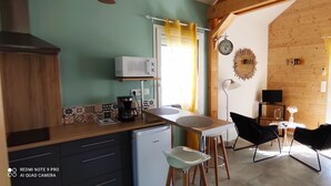A kitchen with a microwave, coffee maker, and a refrigerator. There is a dining area with chairs and a table. - Lovely, cosy little chalet close to a wood (Montardon)